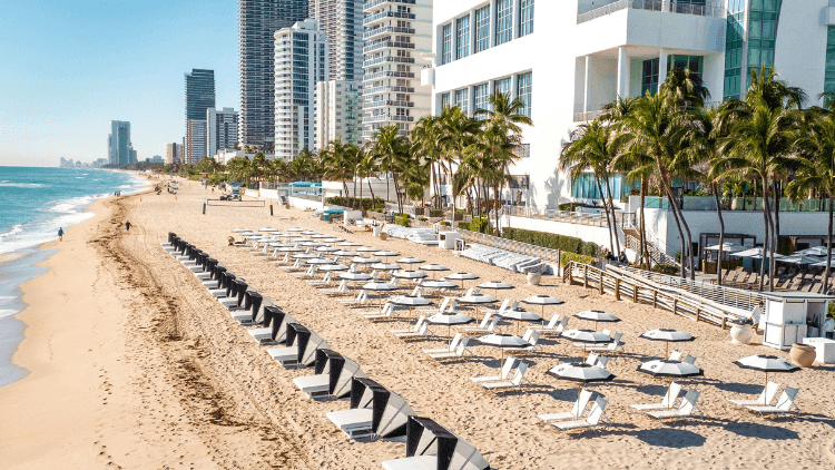 Aerial view of The Diplomat Resort with beach, palm trees, pool, and the ocean under a clear blue sky