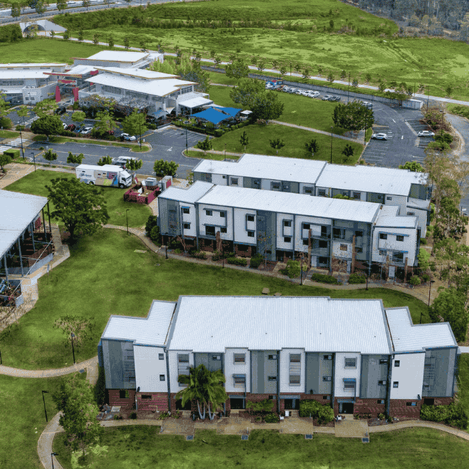 Aerial view of modern two-story residential buildings with white roofs surrounded by green lawns and trees in Springfield Central.