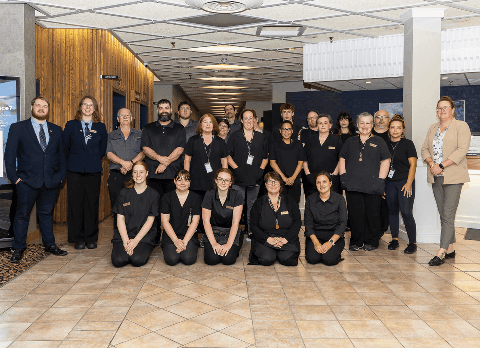 Large group of professional hotel staff members posing together in the lobby reception area at Rodd Hotels & Resorts