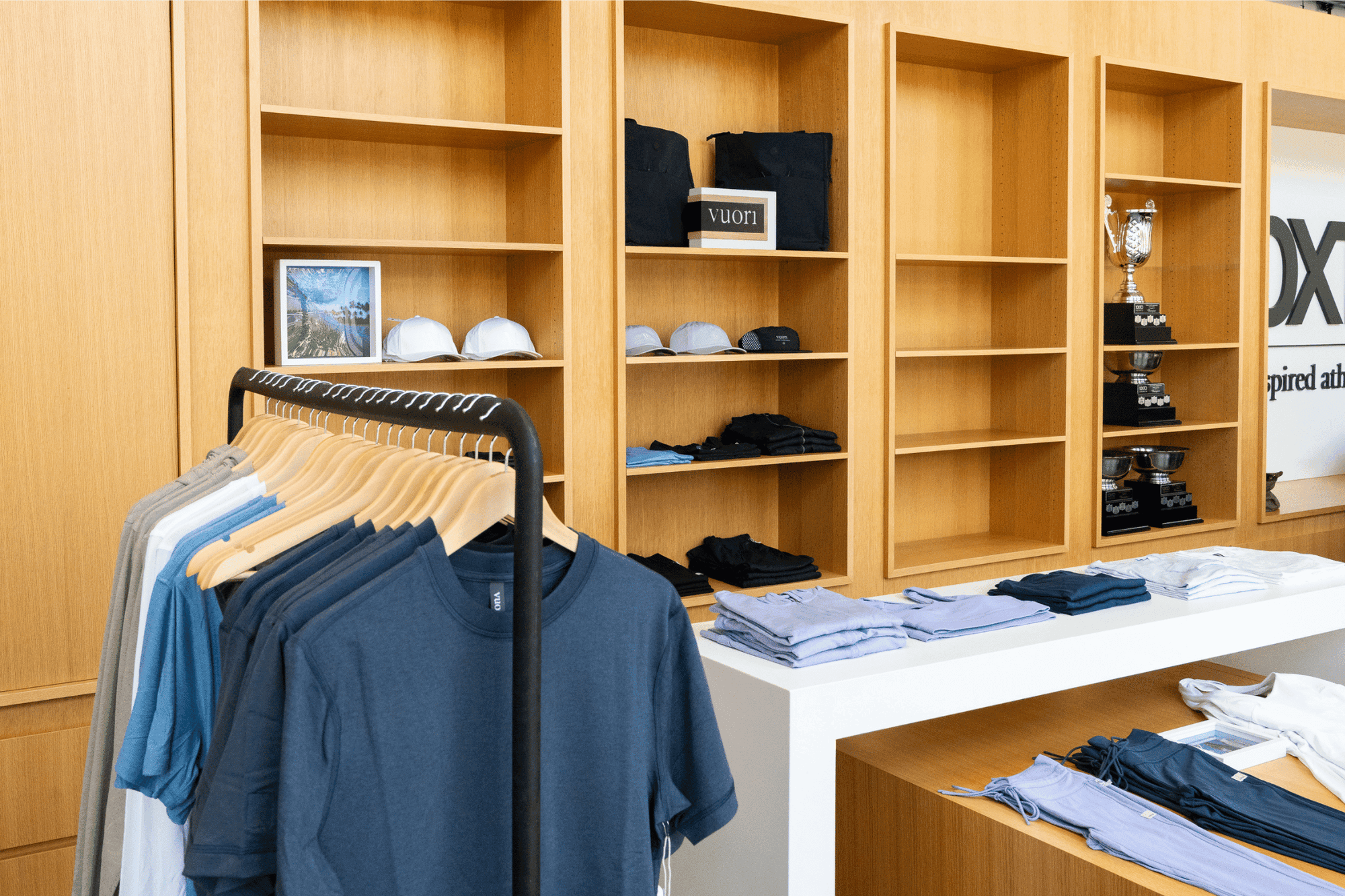 Hotel X Toronto shop with shirts on a rack by folded apparel on tables and hats and trophies displayed on wooden shelves