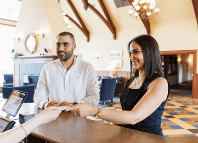 Couple checking in at the reception desk under chandeliers in the spacious lobby at Rodd Crowbush Golf & Beach Resort