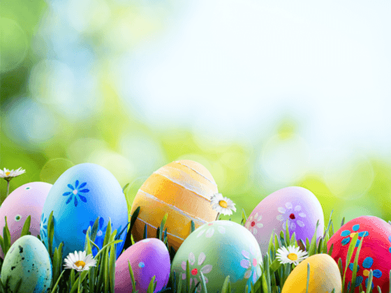 Colorful Easter eggs in green grass with daisies, glowing in soft sunlight at Hotel Cascais Miragem Health & Spa