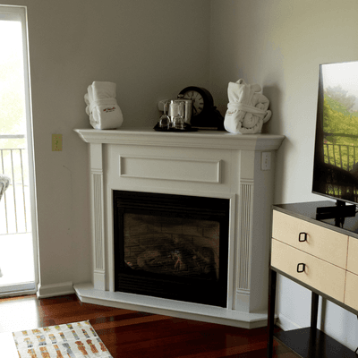 White corner fireplace topped with plush folded robes beside television set in guest room at La Tourelle Hotel and Spa