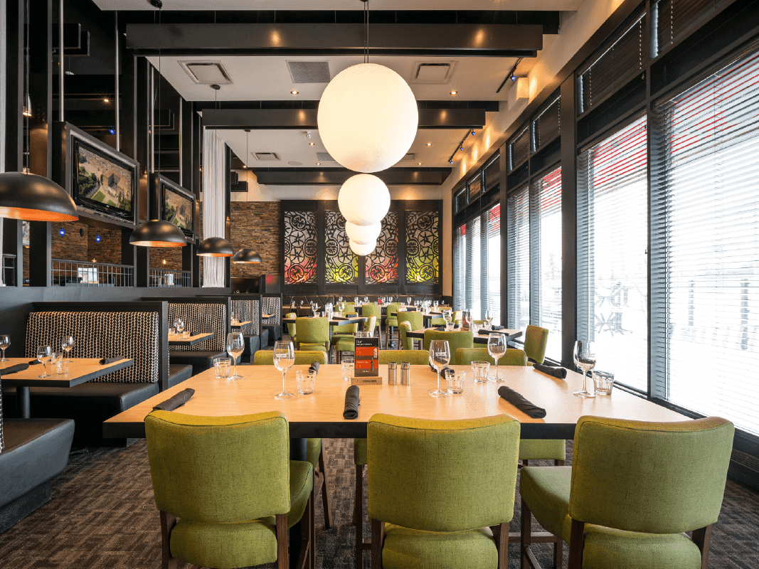 Dining tables set up with comfy chairs in Pacini Restaurant at Acclaim Hotel Calgary