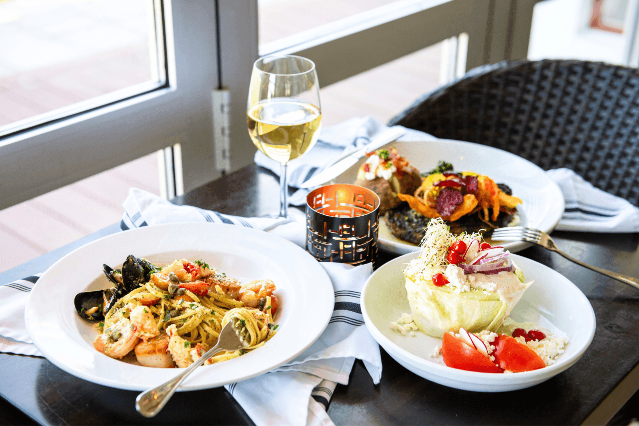 A table set with plates of food, a glass of wine, and a candle.