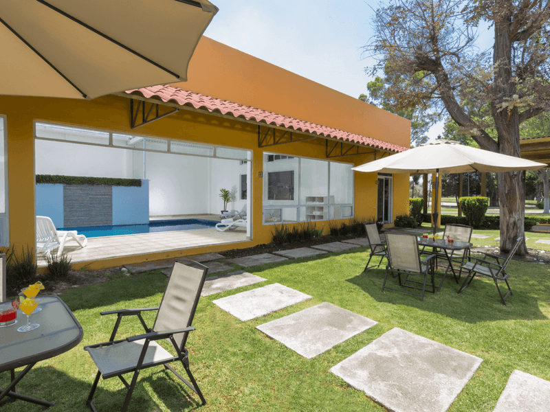 Outdoor dining set-up with canopy, paved pathway with indoor pool view at Hotel Gamma Pachuca