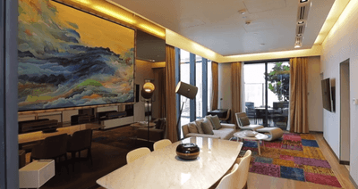 Dining & lounge area with an abstract painting, sofa, and colorful patchwork rug in The Peony Villa at One Farrer Hotel