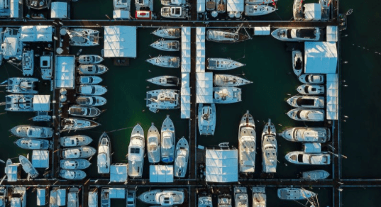boat show. -Aerial view of a marina with numerous boats docked at the piers and some floating in the water.