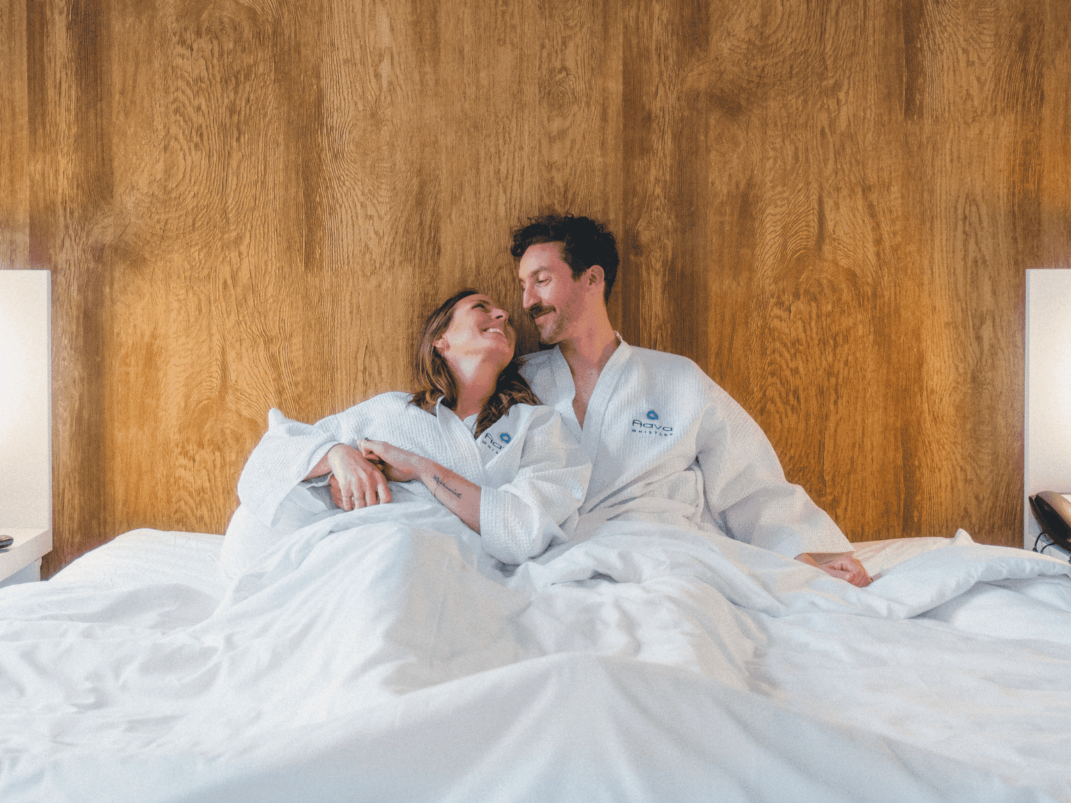Couple cuddling on a bed at Aava Whistler Hotel