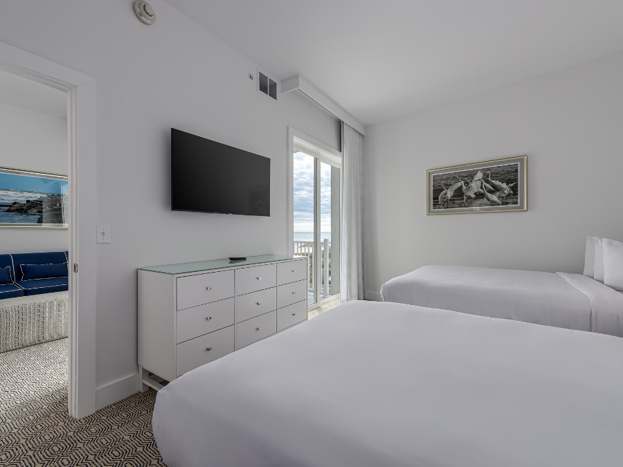 Penthouse Oceanview Suite Bedroom with two fluffy white beds, white dresser, mounted tv