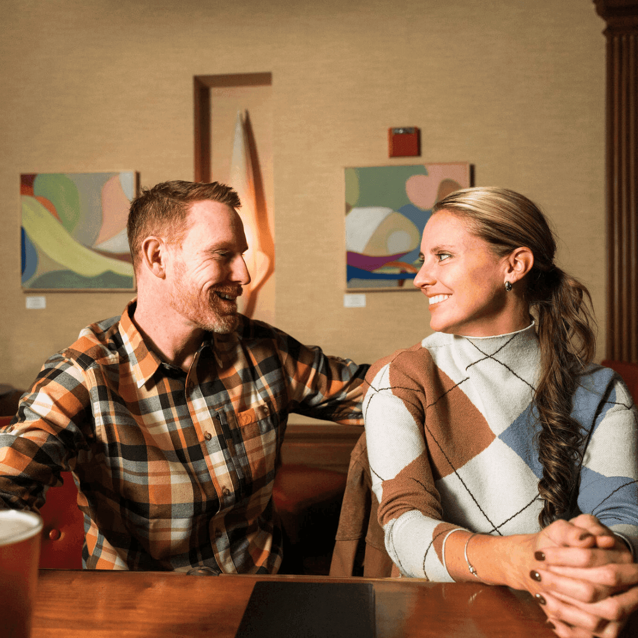 Couple smiling and sitting together at a table with a drink during Valentine’s Dinner at Epoch.