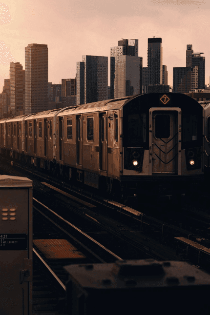 Evening cityscape with subway train passing against towering buildings, capturing urban charm near The Rhyland Hotel