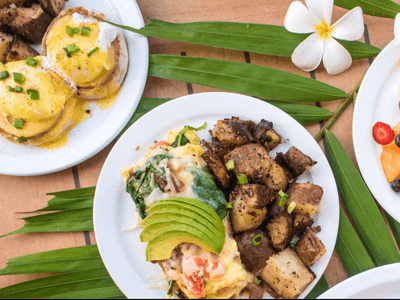Frittata with avocado and roasted potatoes, served with eggs benedict on a wooden table at the Maui Coast Hotel