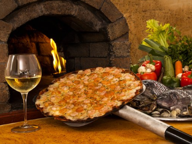Pizza al horno de leña con copa de vino en One Hotels