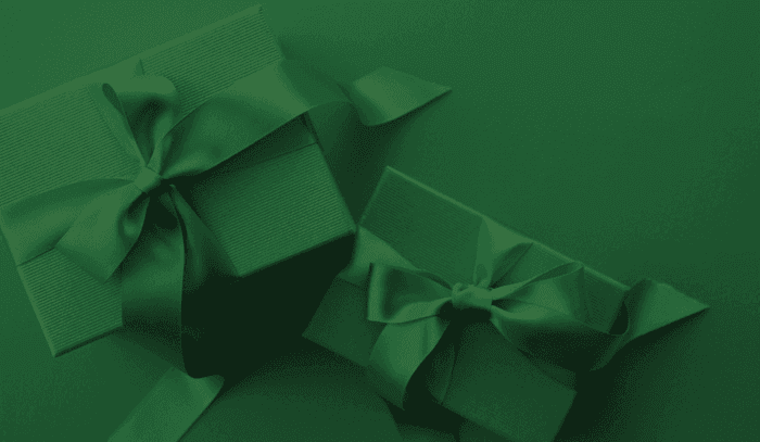 Emerald green gift boxes with silk ribbons on a dark green surface at The Grace Sydney