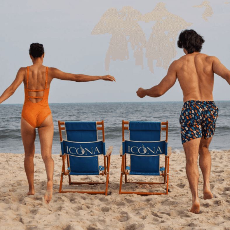 Two people running towards the ocean with ICONA beach chairs between them