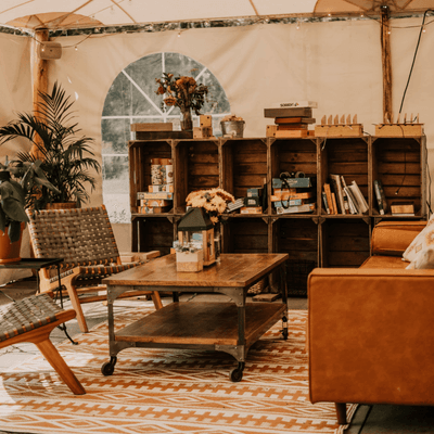 Lounge area with wooden coffee table and leather couch beside rustic crate shelving at La Tourelle Hotel and Spa tent