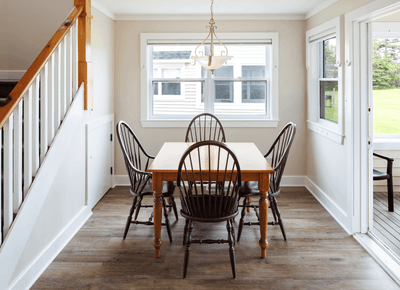Bright dining area with a wooden table, four chairs, and large windows at Rodd Crowbush Golf & Beach Resort