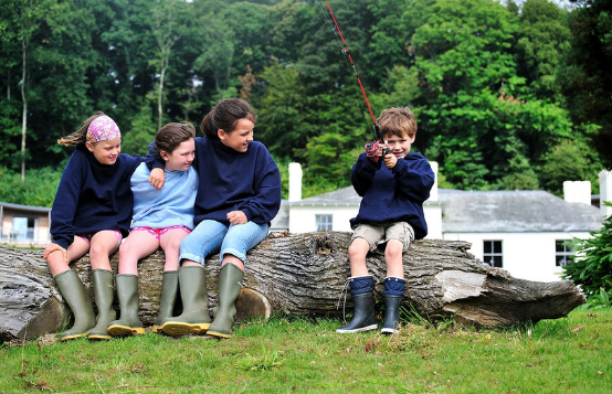 children sitting on log in grounds of Cornwall Hotel