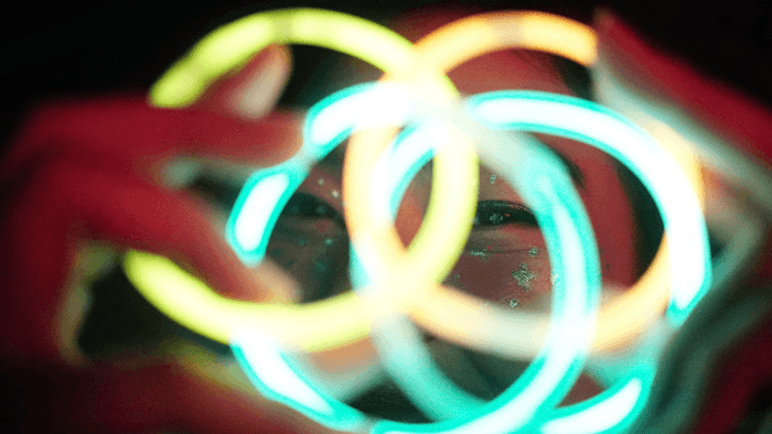 Person's eyes peeking through a tangle of glowing neon light bracelets at The Diplomat Resort