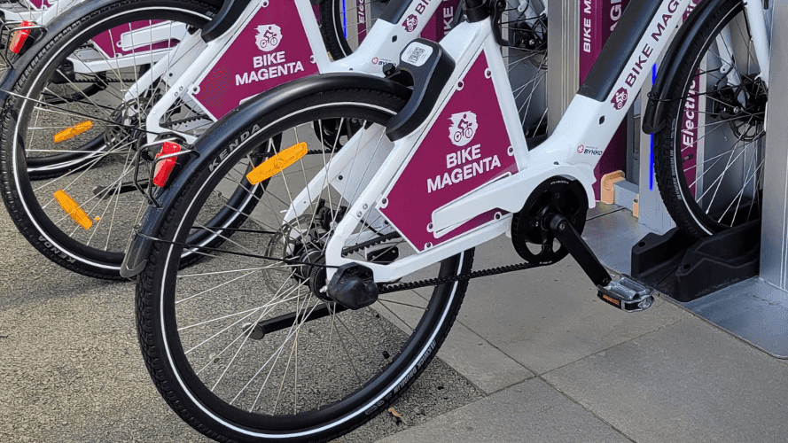 A row of bikes neatly parked in a line on a sidewalk at Pullman Magenta Shores
