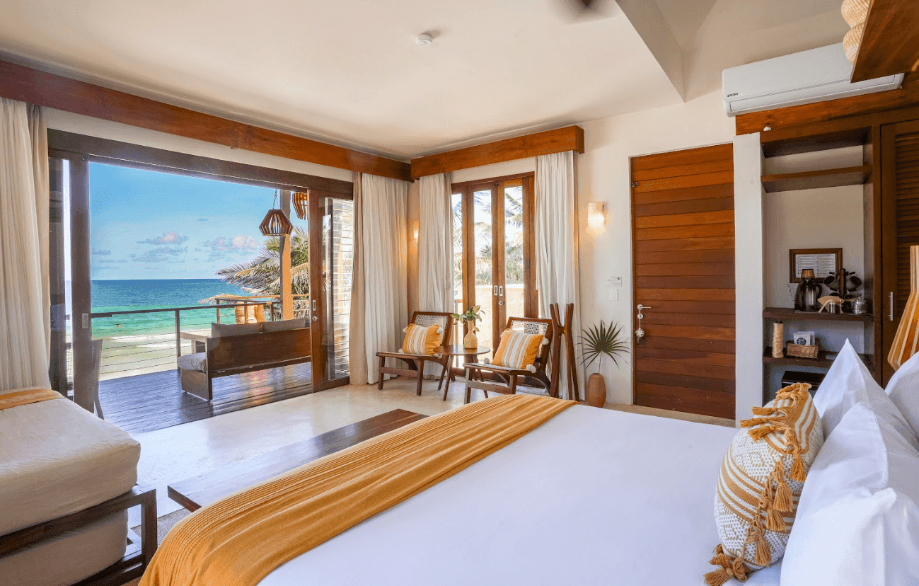 Bright La Zebra Tulum beachfront suite with a king bed and ocean-view balcony.