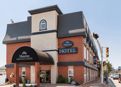 Red brick exterior and main entrance under a black rounded canopy with hotel signage along street corner at Rodd Moncton