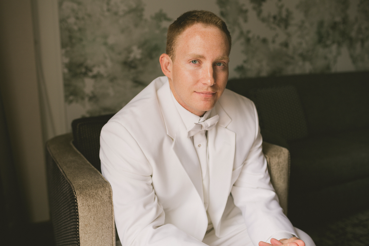 Groom dressed in white suite at The Grove Hotel