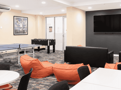 Modern student recreation room with orange bean bags, ping pong table, foosball table, and wall-mounted TV at Student Living - Waymouth
