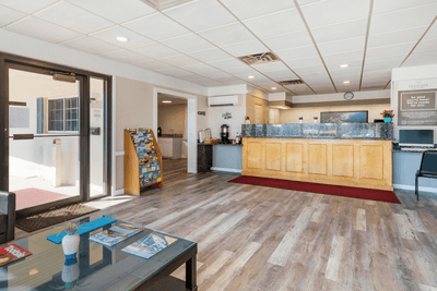 Bright lobby at Ogunquit Hotel and Suites with reception desk, coffee station, brochures, modern decor, and wooden floors