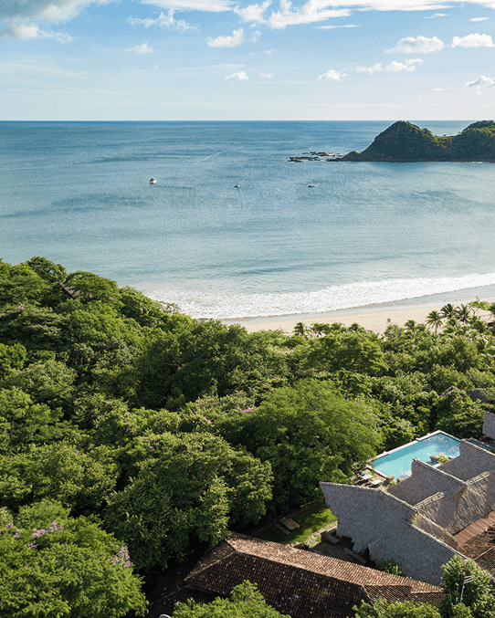 Aerial view of the lush tropical forest and turquoise ocean bay near Morgan's Rock Reserve & Ecolodge, Nicaragua