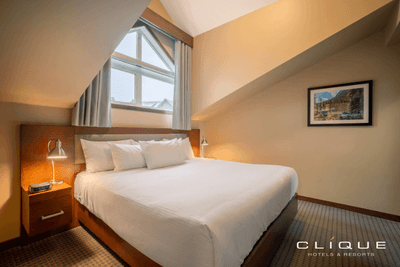 Bedroom at Falcon Crest Lodge features a comfortable king-size bed, bedside lamps, and a unique angled window