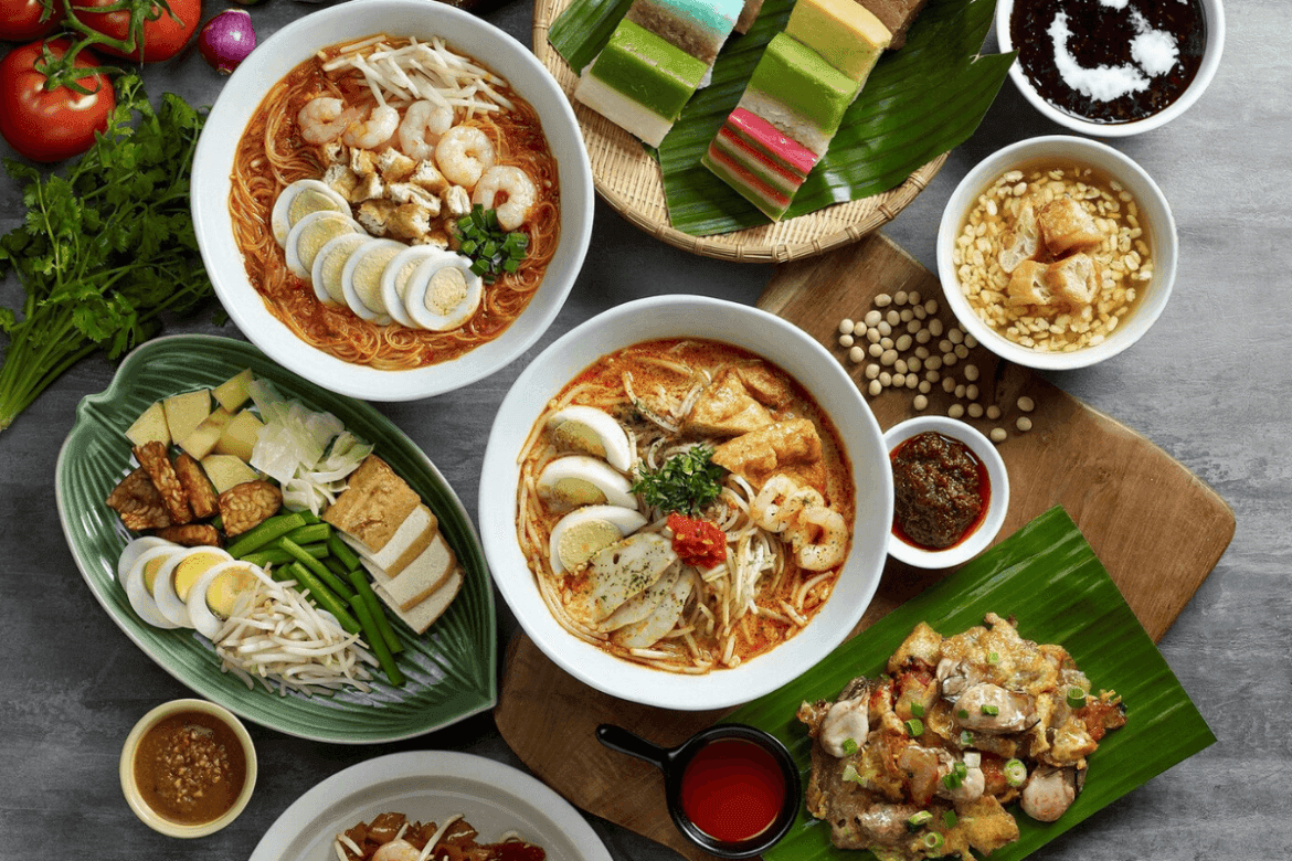 Various dishes with noodles, tempeh, eggs, and layered cakes on a table at Sunway Velocity Hotel