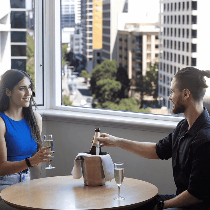 A couple enjoying bubbles with city views in their room