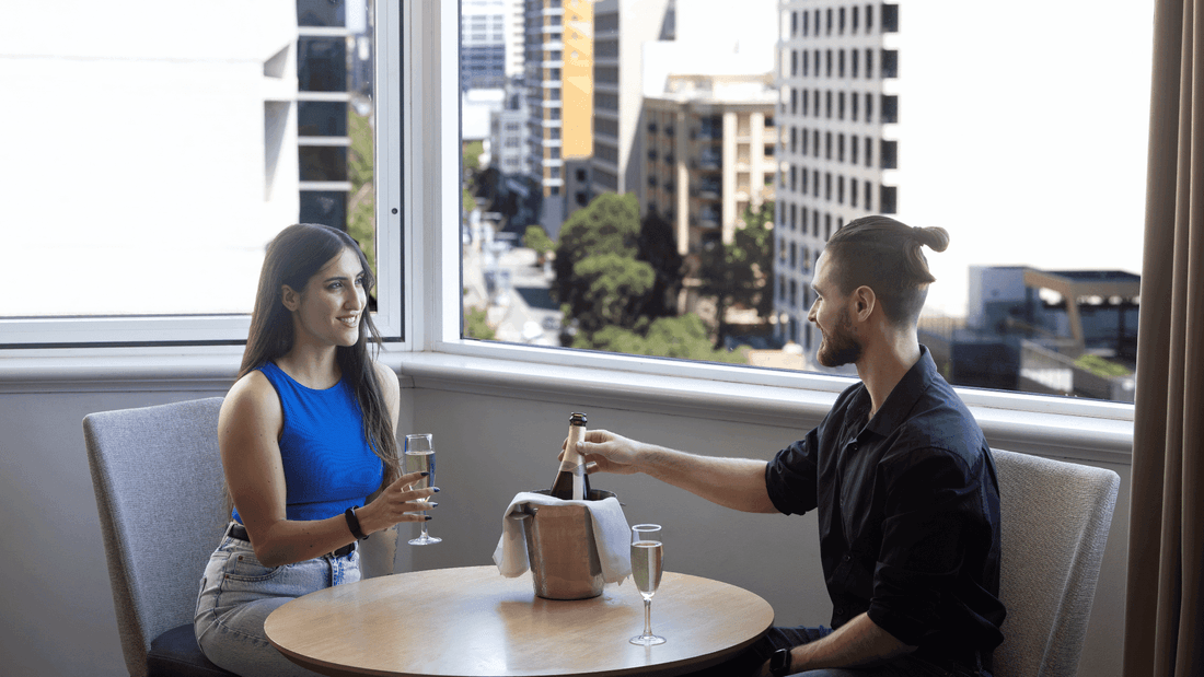 A couple enjoying bubbles to celebrate their getaway with city view 