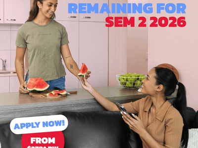 Two students sharing watermelon in a modern kitchen with white cabinets and a fruit bowl at UniLodge Darwin