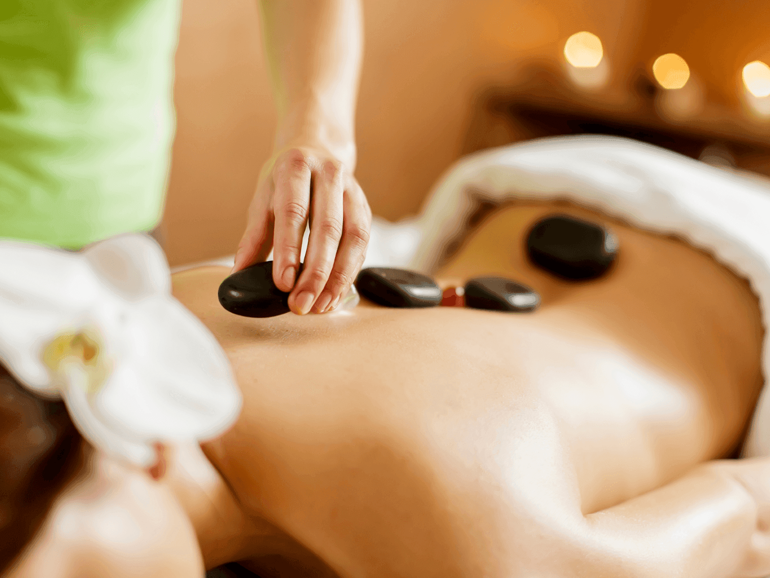 Woman having a hot stone session in the spa at Ana Hotels