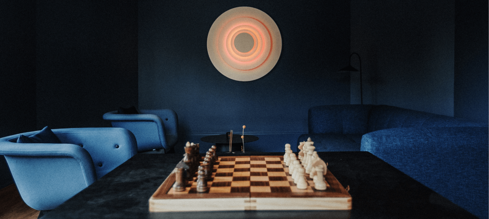 Low lighting meeting space with a marbled chess set inbetween a set of chairs
