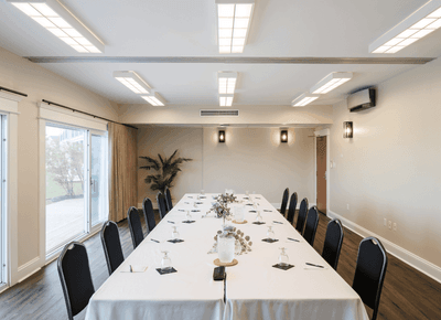 Bristol/Canavoy with long white tables and black chairs placed under ceiling lights at Rodd Crowbush Golf & Beach Resort