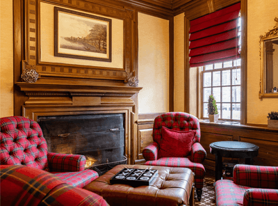 Cozy sitting area at The Exeter Inn with a fireplace and red plaid armchairs, perfect for relaxing