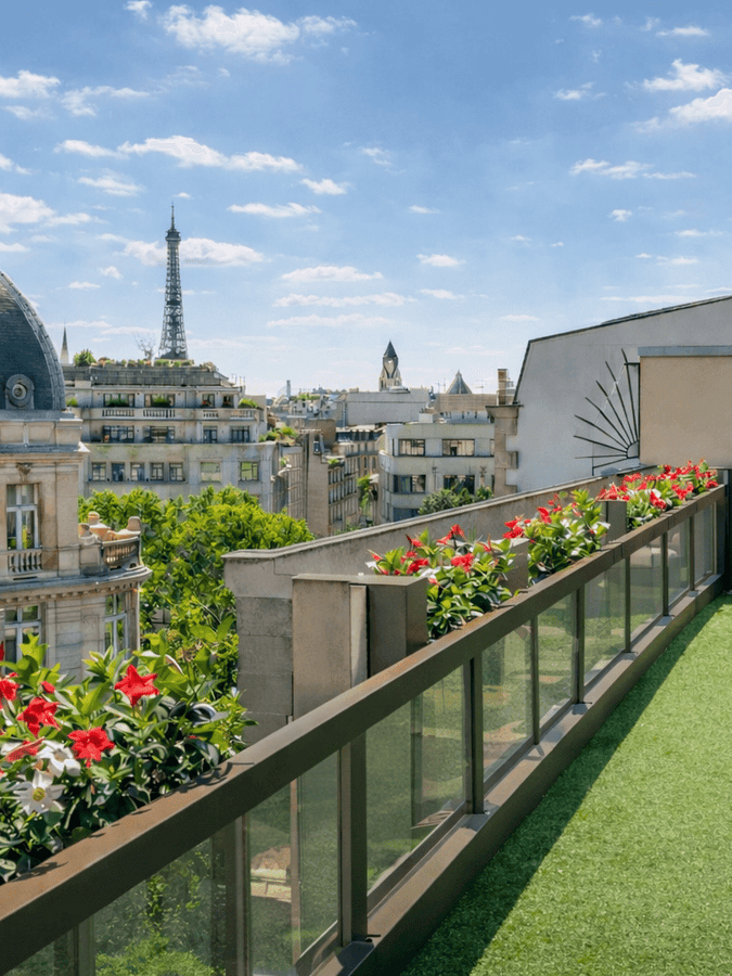 Vue sur les toits de Paris et sur un balcon agrémenté de gazon et de plantes au Warwick Champs-Élysées Paris.