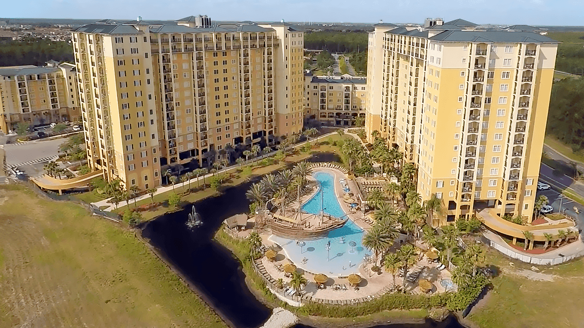 An aerial view of a large hotel complex with a pool and palm trees.