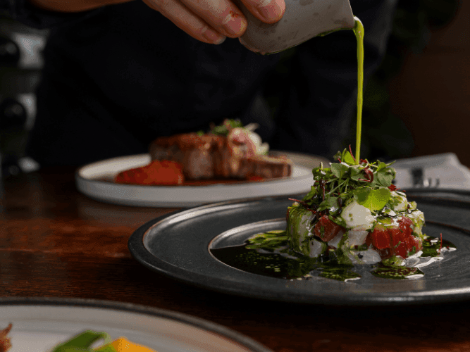 Close-up of chef garnishing the dish in Bacar Restaurant at Pullman Sydney Olympic Park