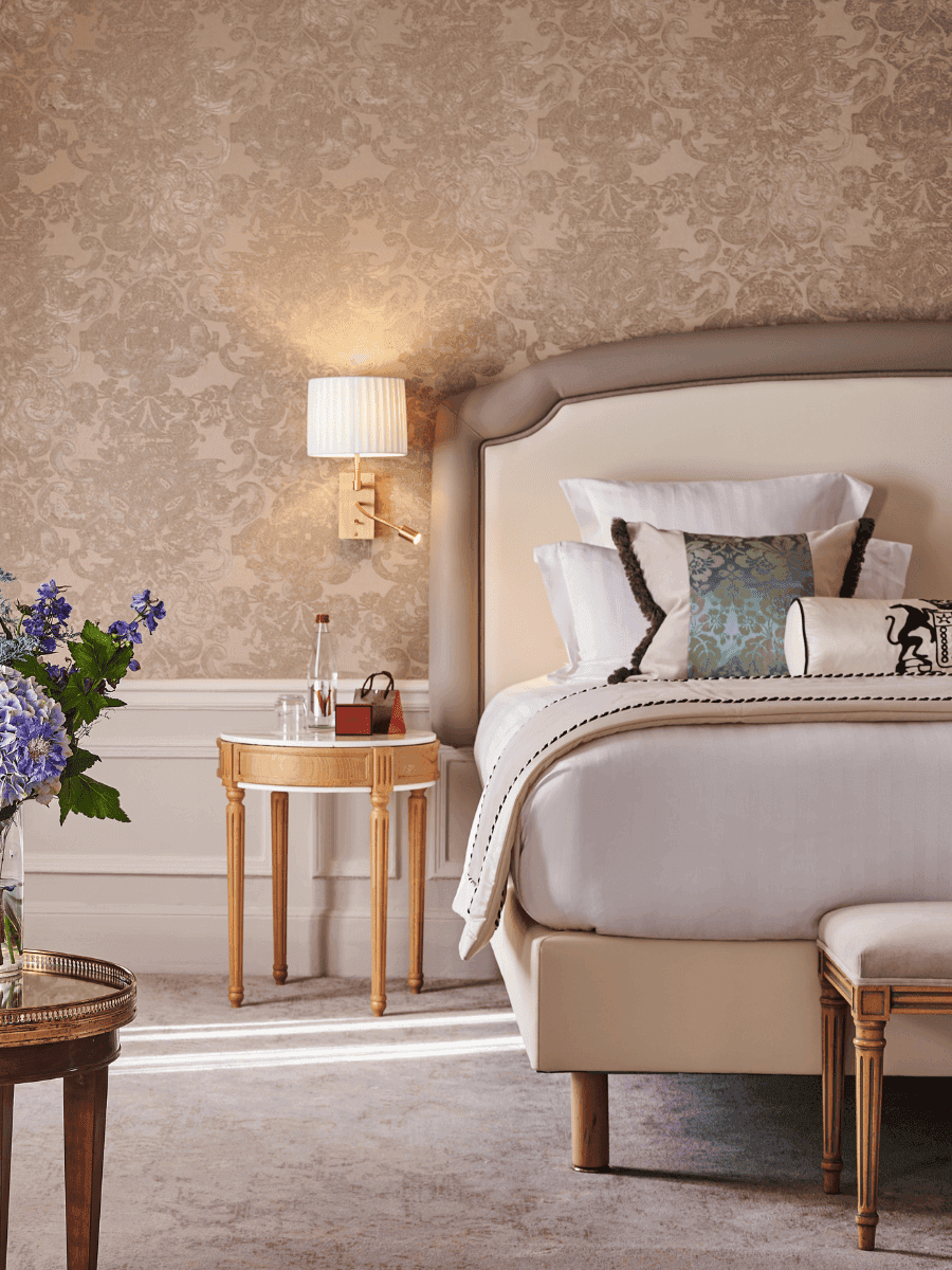 Bed with side table and couch near window in Prestige Suite – Rue de la Paix View at Hotel Westminster Paris