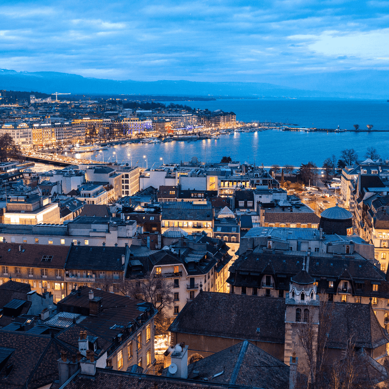Twilight cityscape with illuminated buildings and waterfront view showcasing urban charm and serene ambiance.