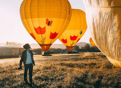 Man standing next to hot air balloons in a field
