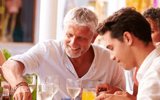 People enjoy drinks and food at a festive table in Amora Hotel Sydney, smiling and having a great time