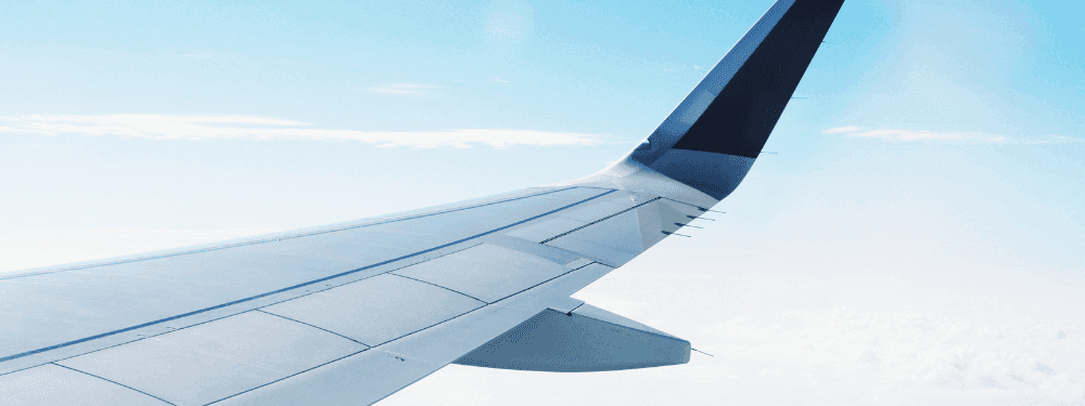 Airplane wing gliding above white clouds under a blue sky near Novotel Sydney International Airport