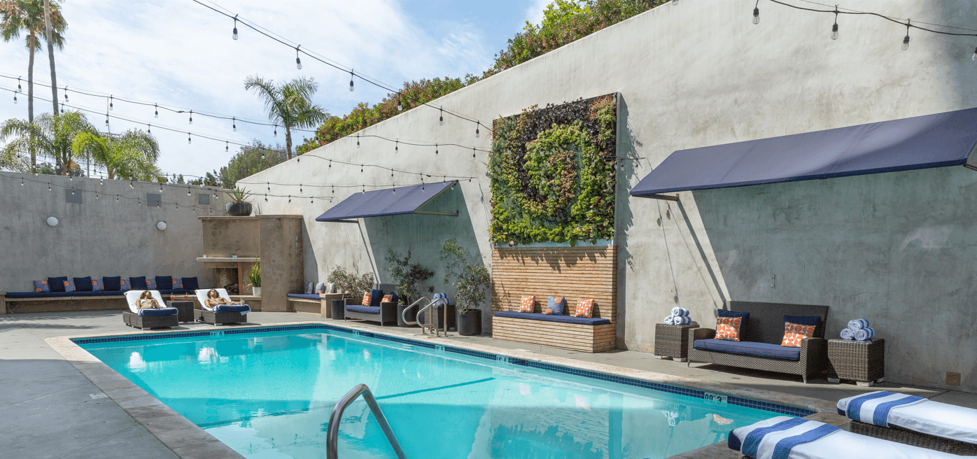 A swimming pool with lounge chairs and a wall with plants.