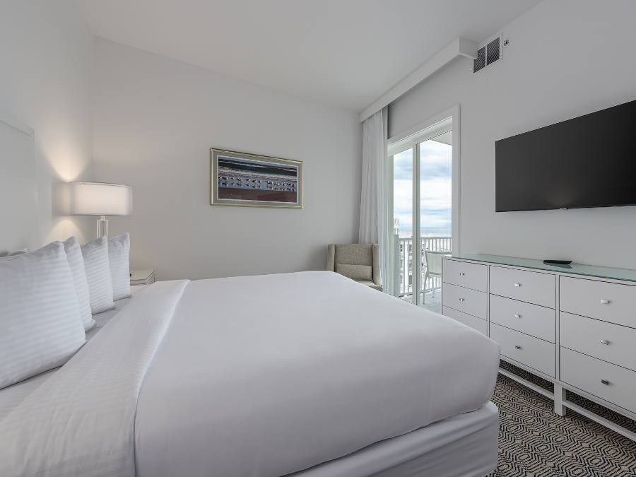 ICONA Diamond Beach NJ Penthouse Oceanview Suite White King Bed, Dresser, TV, & Ocean view through the window